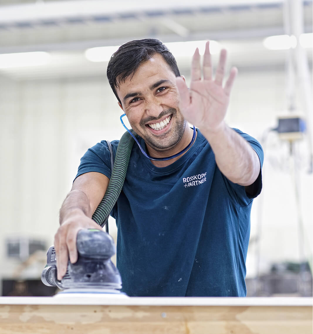 Mitarbeiter beim Arbeiten winkt in die Kamera